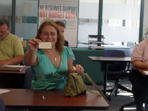 Mandi Kinder holds up a truama informed card at a peer specialist training. "Please be respectful to me," it says, "I can become confused and scared in situations with a large power differential and a perceived loss of control or voice."