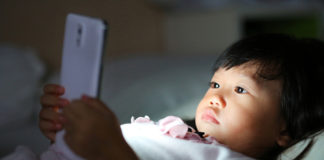 “Virtual Autism” May Explain Explosive Rise in ASD Diagnoses child looking at smartphone