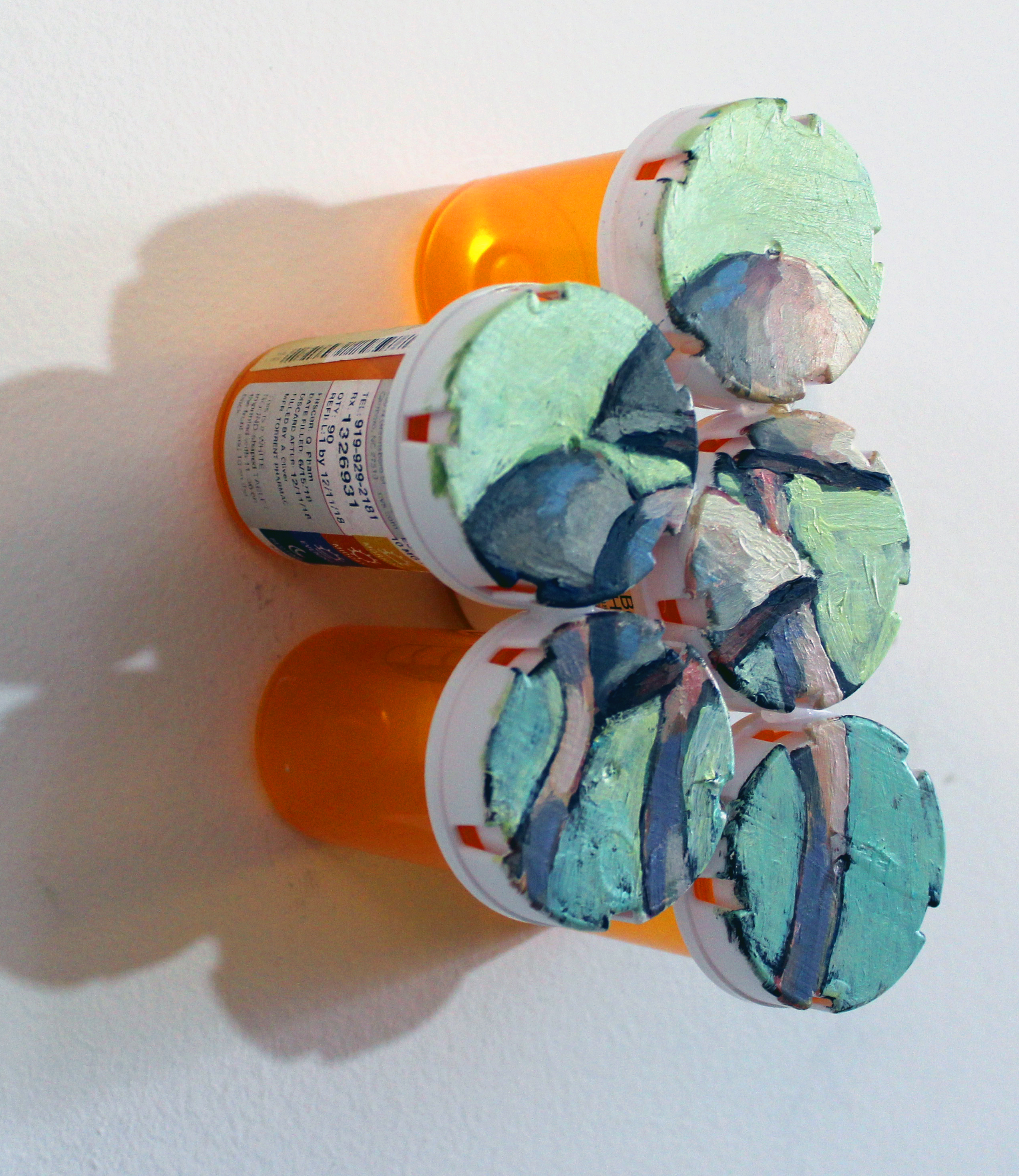 Pill bottles with mosaic pasted to the tops