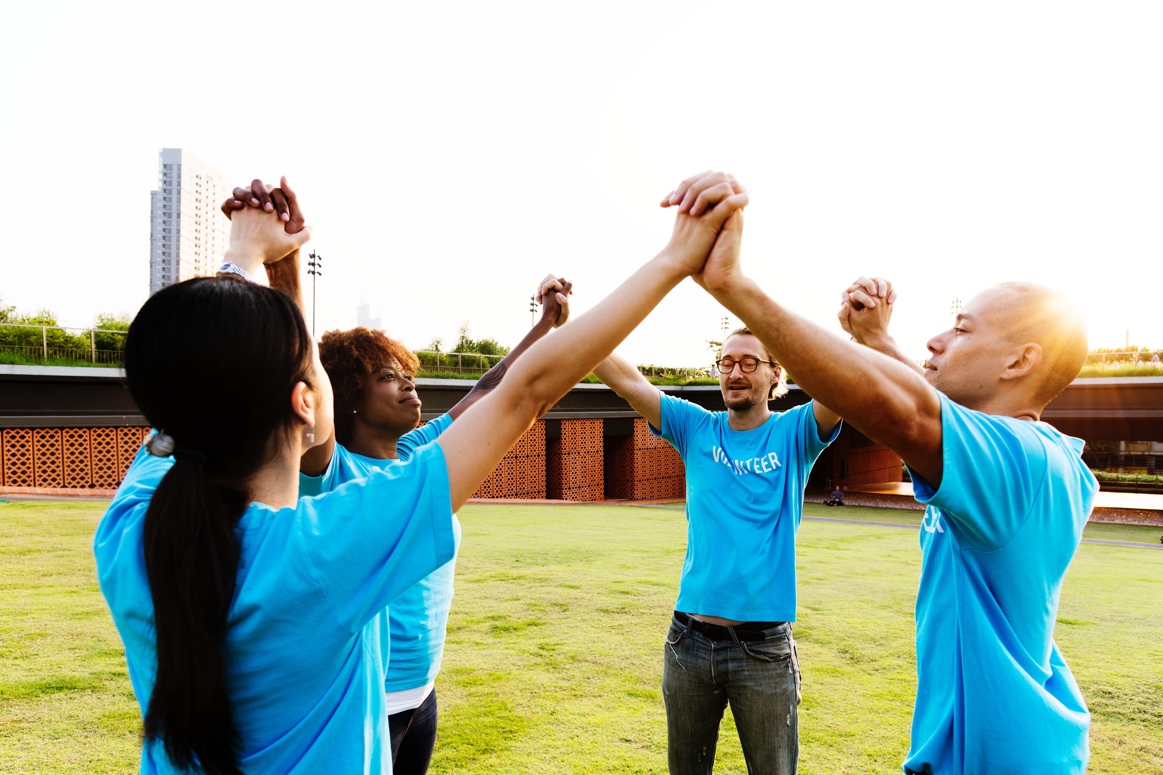 Four standing people holding raised hands outside