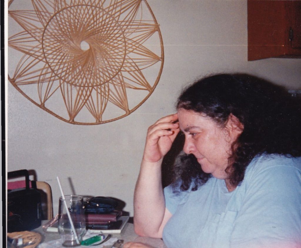 Woman sits at a table with an empty glass with a straw on it, a alighter, and a small portable cassette player.