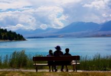 Meaning in Life Linked With Health, Cognitive Functioning from behind, grandmother sits with two children overlooking a lake