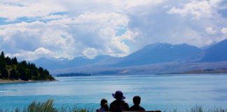 Meaning in Life Linked With Health, Cognitive Functioning from behind, grandmother sits with two children overlooking a lake