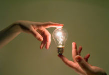 Rethinking “Delusions”: Envisioning a Humanistic Approach to Troublesome Beliefs two hands touching a lightbulb