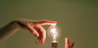 Rethinking “Delusions”: Envisioning a Humanistic Approach to Troublesome Beliefs two hands touching a lightbulb