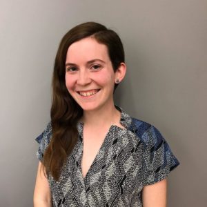 A young white woman with an undercut and long hair smiles.