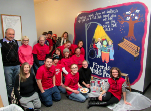 group of about 20 people inside by a mural