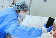 How Tech Connects Older People with Mental Health Services A masked doctor holds a phone up to a patient's face.