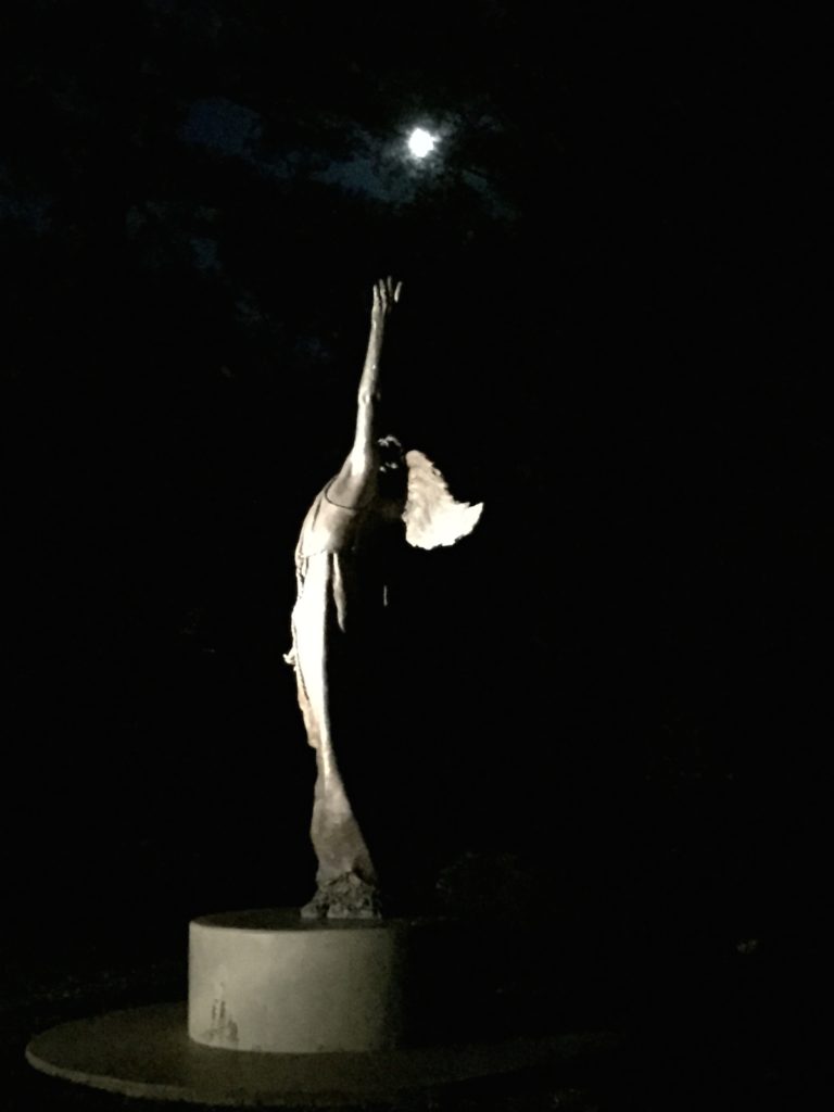 Moonlit statue of an angel reaching for the moon.