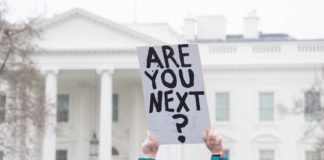 Who Is a Danger to Others: The “Mentally Ill” or the Powerful? Protester holding up sign "Are you next?" in front of the White House