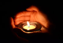 The Smoldering Wick: Suicide and Faith hands holding a candle in the dark