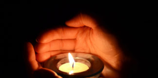 The Smoldering Wick: Suicide and Faith hands holding a candle in the dark