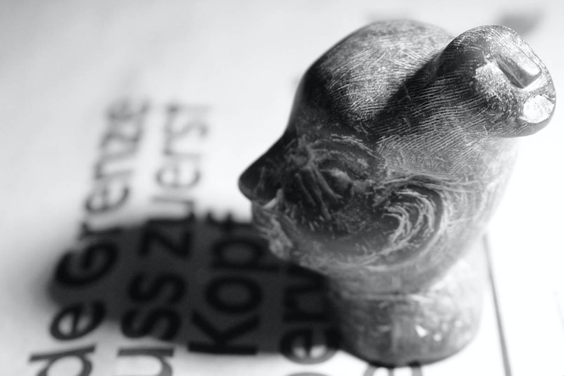 Soap stone carving of a buddha on a newspaper clipping headlined "Every limit must first be overcome in the head"