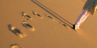 To the Young Person Who Doesn’t Identify with Their Disability Diagnosis Anymore woman walking away, footprints in the sand