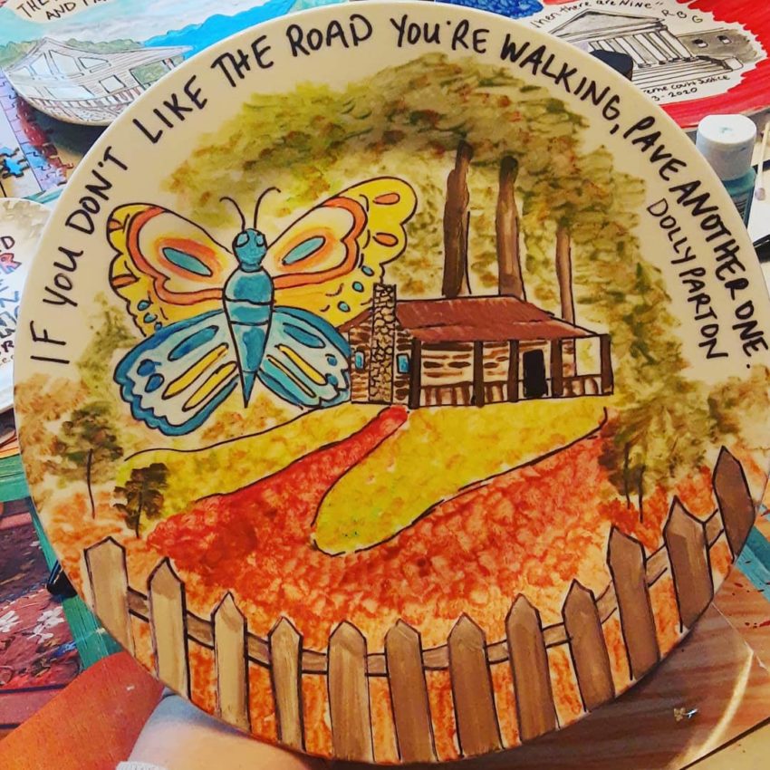 A plate painted with a butterfly and house with the words "If you don't like the road your walking, pave another one"