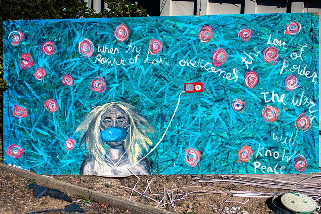 large mural of a young woman laying in the grass listening to music and wearing a mask