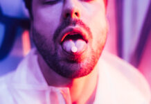 Psychedelics—The New Psychiatric Craze Photograph of man's lower face with a pill on his tongue