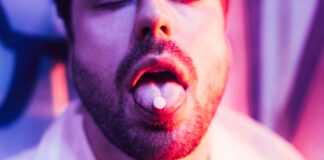 PsychedelicsâThe New Psychiatric Craze Photograph of man's lower face with a pill on his tongue