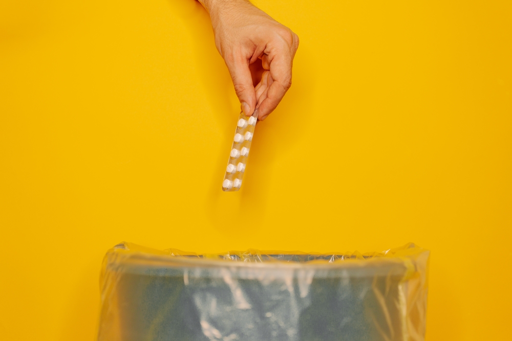 Photo of a hand throwing pills in the trash