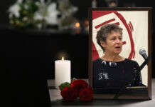 Remembering Darby Penney — A Fierce Advocate for Justice and Human Rights Photo of Darby Penney sitting beside a flower and candle
