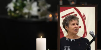 Remembering Darby Penney — A Fierce Advocate for Justice and Human Rights Photo of Darby Penney sitting beside a flower and candle