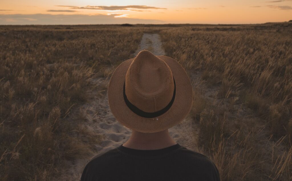 photo of a person from the back looking at a sunset over a long road