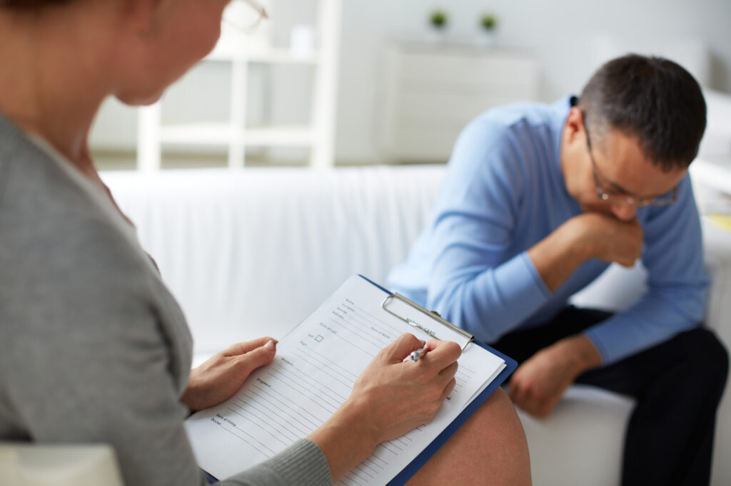 Female psychologist consulting pensive man during psychological therapy session