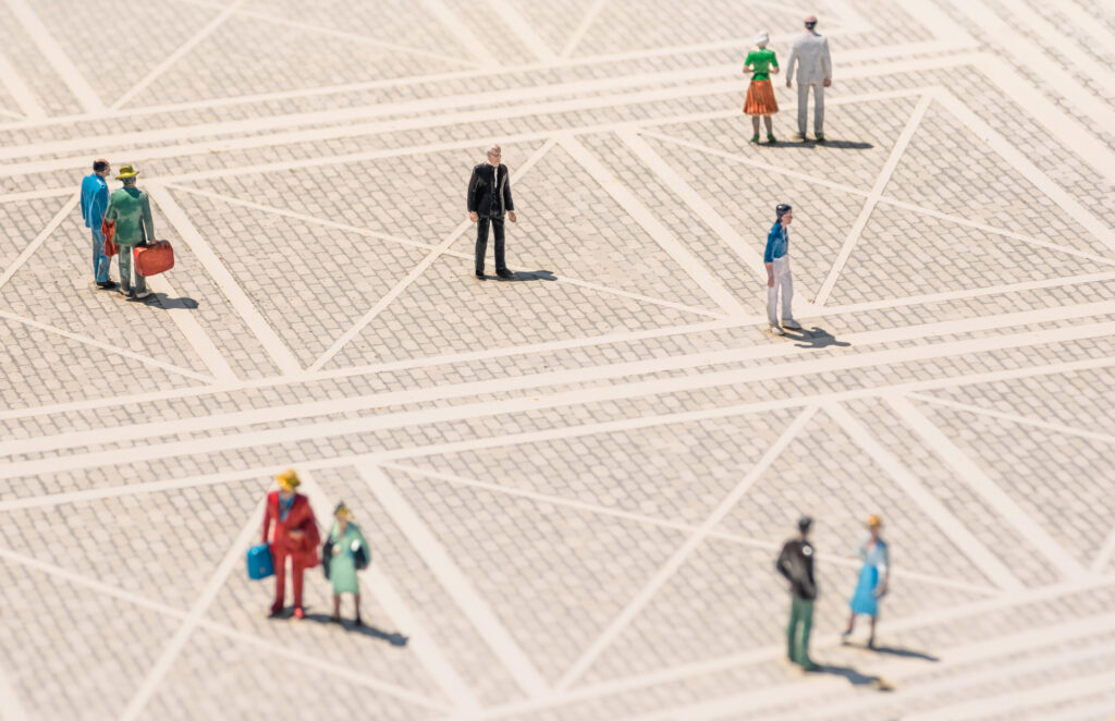 Lonely man standing lost in the middle of a generic square with normal people aroun