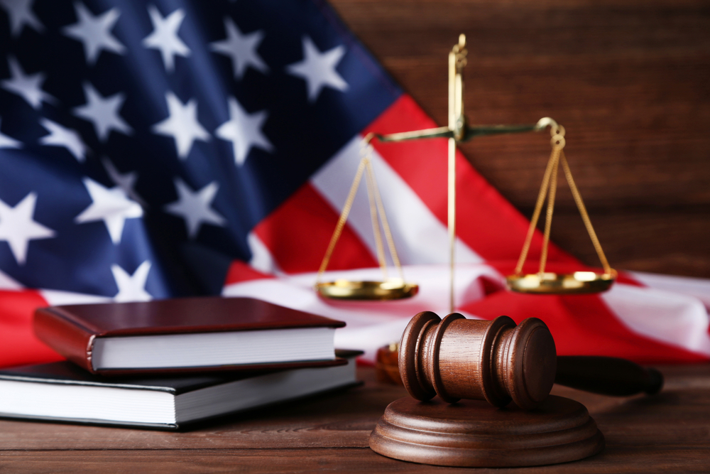 Judge gavel with scales, books and american flag on wooden table