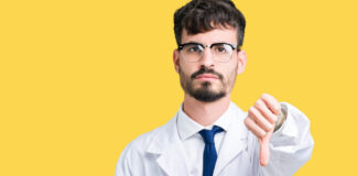 Collateral Damage: The Negative Impact of Antidepressants on New Zealand Youth Young professional scientist man wearing white coat over isolated background looking unhappy and angry showing rejection and negative with thumbs down gesture. Bad expression.