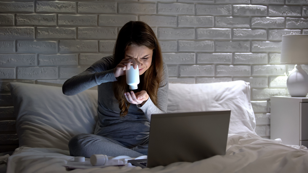 Girl, looking confused, holding pill bottle