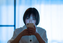 Evidence Lacking for Mobile Mental Health Apps A woman staring at a smartphone with a stern look in the room