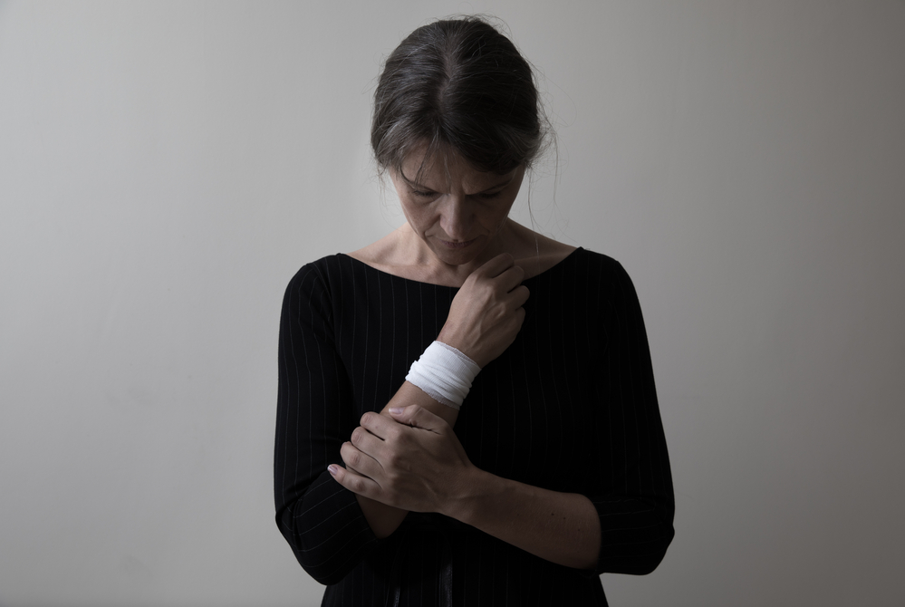 A photo of a woman holding her bandaged wrist