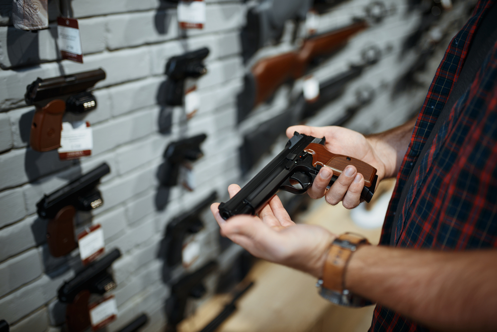 Man holds handgun in gun shop. 