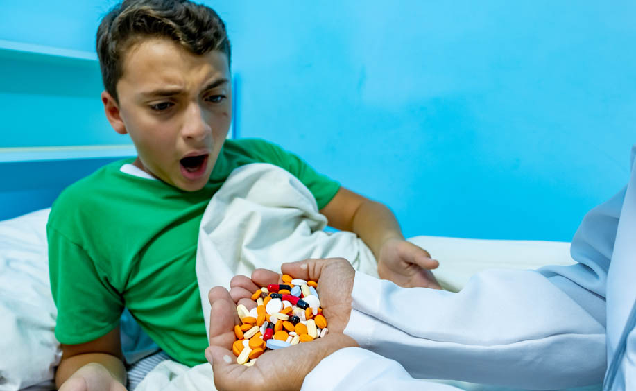 A child looks shocked to receive an overflowing handful of pills