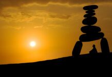 Inside a Forensic Psychiatry Unit: Cultivating the Superpower of Equanimity Silhouette against sunset: A person sits and meditates under a tower of stones