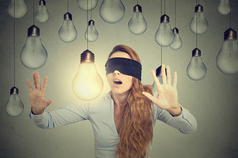 Concept illustration: Blindfolded young woman walking through lightbulbs