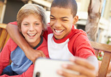 Encouraging Healthy Masculinities Can Protect Against Discrimination and Bullying Two Boys Sitting On Bench In Mall Taking Selfie