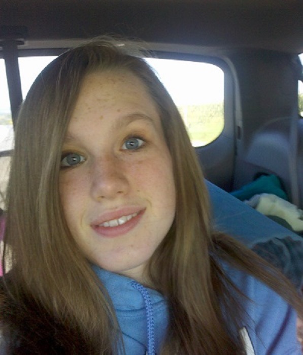 a young, smiling white girl in the backseat of a car