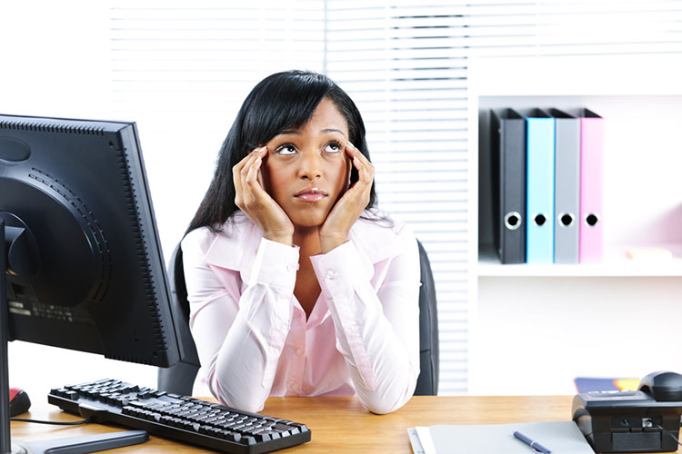 Stock photo of an unhappy young black business woman at desk in office