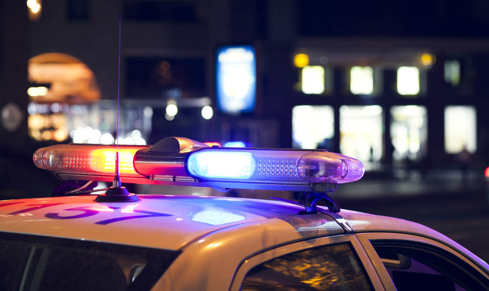 Blue light flasher atop of a police car. City lights on the background.