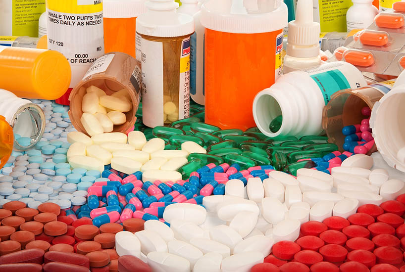 Photo of a number of empty and full pill bottles with a colorful variety of pills piled all over