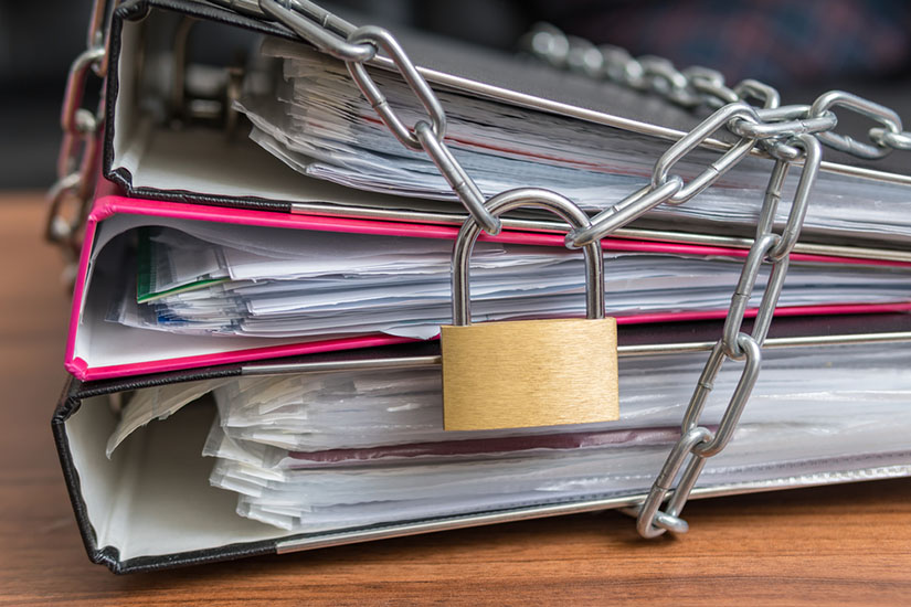 Photo of a padlock chaining a set of document binders