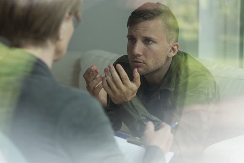 Photo of a man, a veteran in a military uniform speaking with a therapist