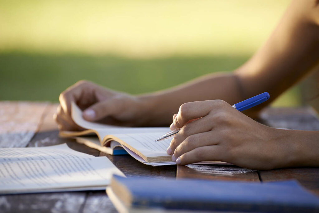 Close-up photo of hands writing in a journal or notebook