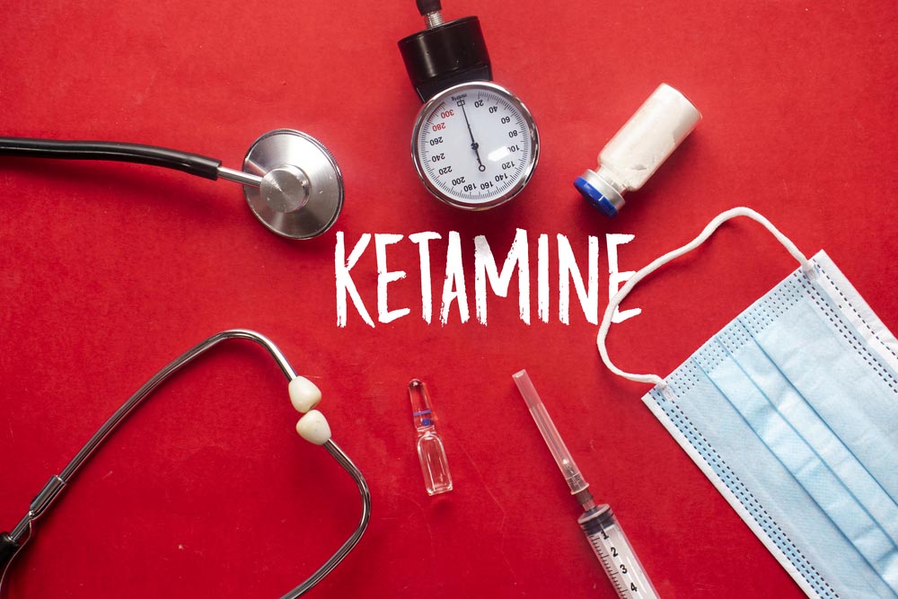 A photo of various medical instruments on a red background with the word "ketamine" in white in the center