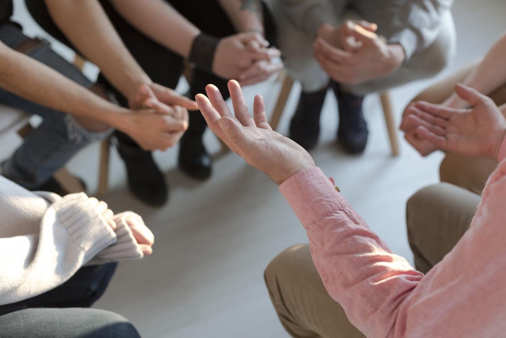 Close-up of therapist's hands explaining a problem to his patients