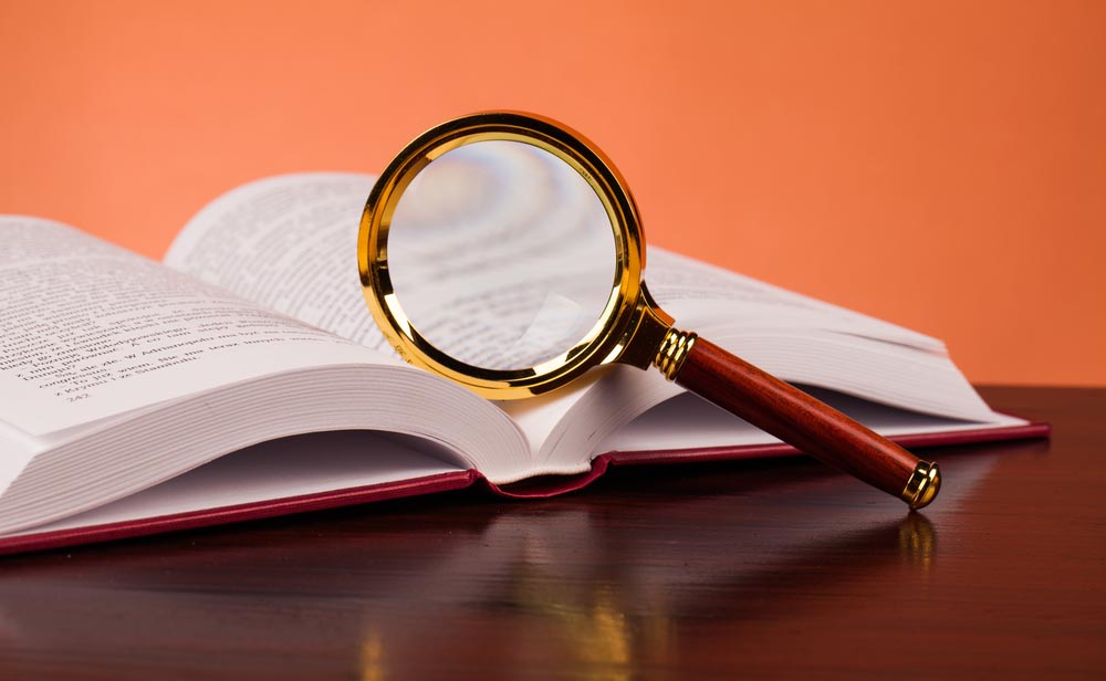 Photo of a magnifying glass sitting on an open textbook