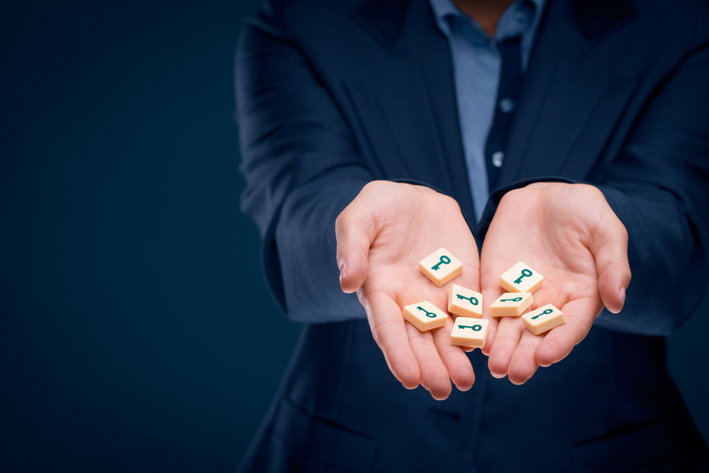 A photo of hands holding wood tokens printed with a key design