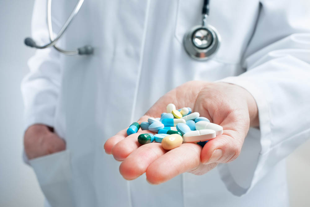 Hand of doctor holding many different pills